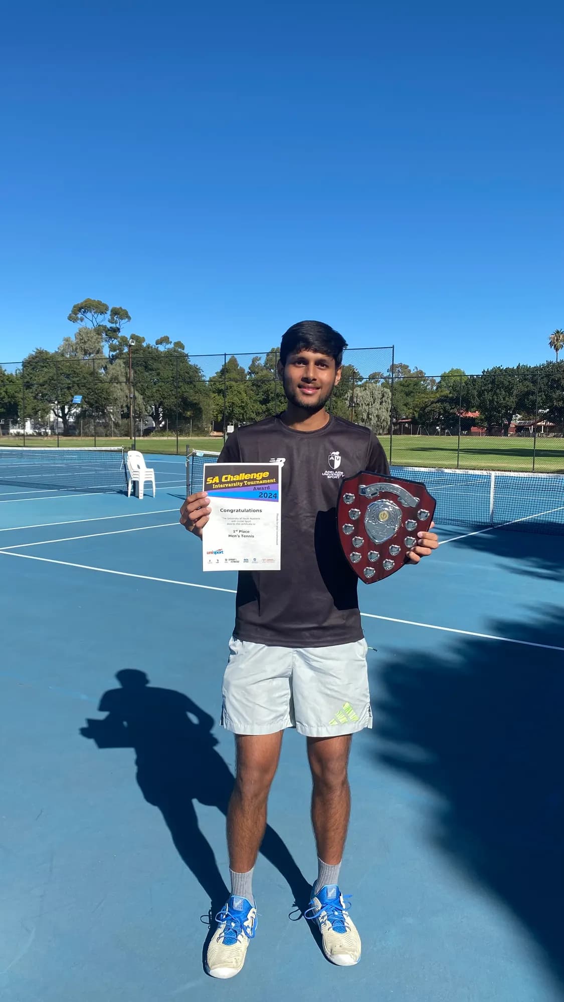 Agrim with a winner's certificate and shield on court