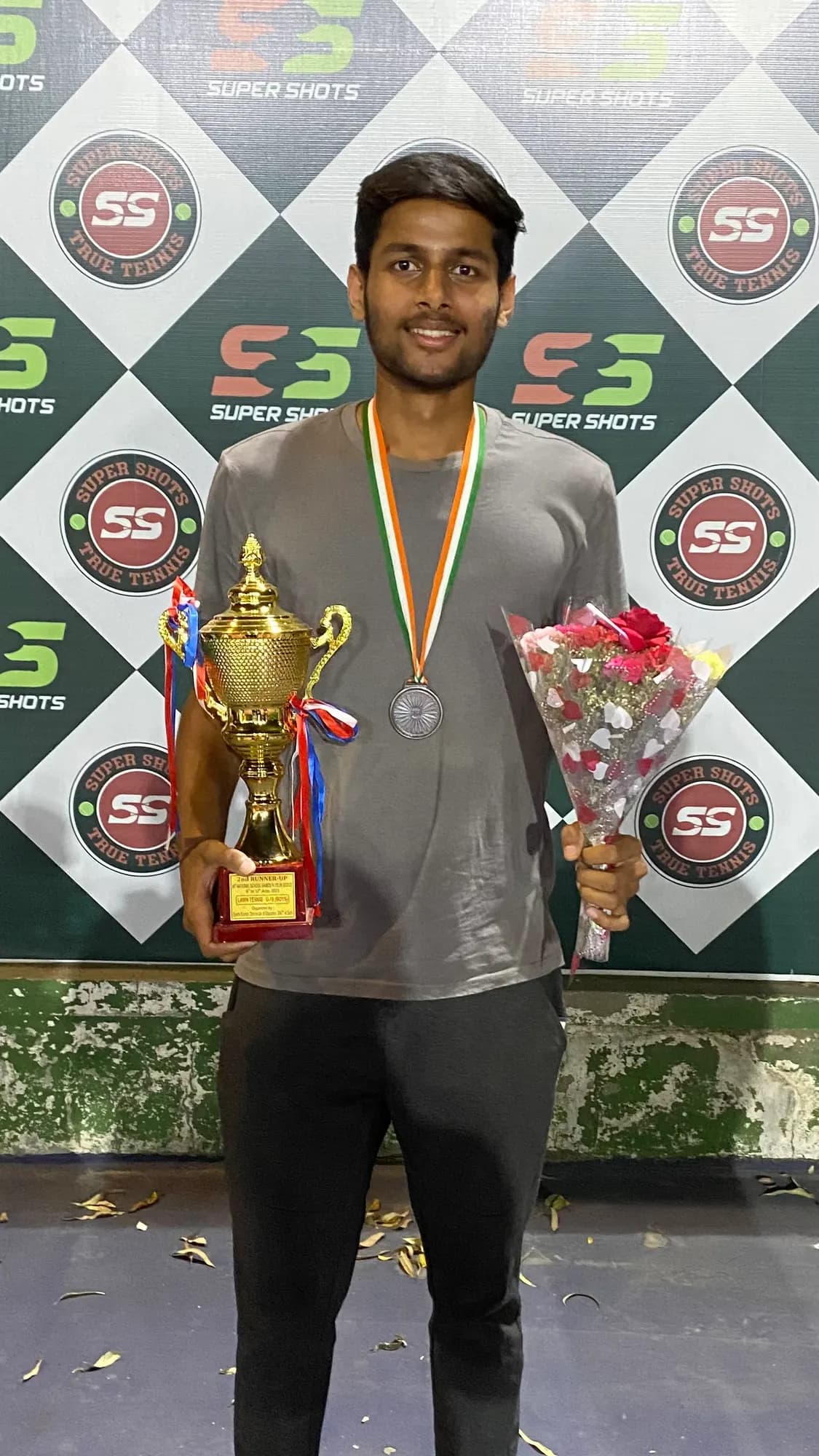 Agrim holding a trophy and medal